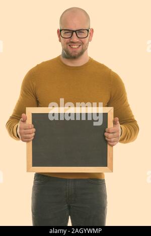 Portrait de jeune homme musclé chauve happy smiling while holding blank blackboard Banque D'Images