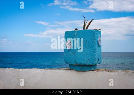 Un pot de fleurs bleu sur le mur de la promenade du bord de mer donnant sur la mer Méditerranée à Hergla, Tunisie Banque D'Images