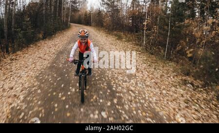 L'un des enfants de race blanche rides moto road in autumn park. Little girl riding noir orange cycle en forêt. Enfant va faire location sports. Motion Biker ride Banque D'Images