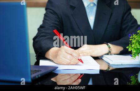 Main tenant stylo rouge à relire sur tableau noir in office Banque D'Images