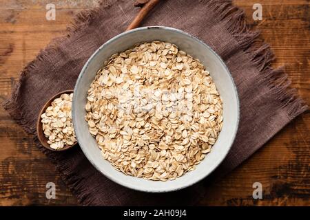 L'avoine, de flocons d'avoine ou flocons d'avoine dans un bol sur la table en bois, surface de toile de fond. Vue d'en haut. Manger des aliments sains, propres et suivre un régime concept. Ensemble Banque D'Images