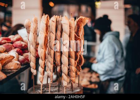 Du pain sur un bâton rouge et petits pains hamburger cuit dans un poêle à bois avec du marché du chocolat porc chocolART à Tübingen, Allemagne avec cabines et Noël Banque D'Images