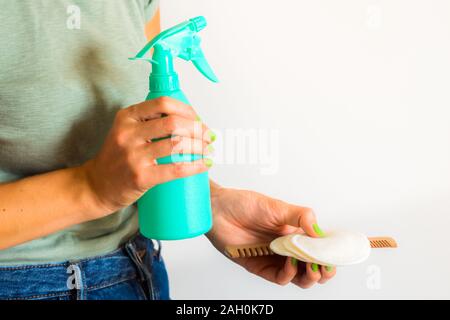 Woman wearing green t-shirt coton réutilisables holding, peigne en bois et bouteille de jet avec du détergent. Concept zéro déchet en routine beauté Banque D'Images