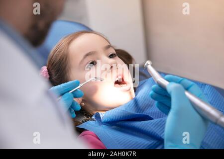 Young caucasian girl calme et heureuse la visite du dentiste dans la prévention et le traitement de la cavité orale. Enfant et médecin tout checkup des dents. Vie saine, santé et médecine concept. Banque D'Images