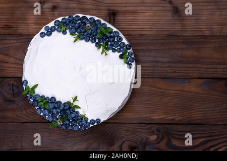 Cheesecake appétissant oreiller biscuit blanc décoré de menthe crème de bleuets et se dresse sur la table rustique en bois. Gâteau sucré avec pièce sur la plaque Banque D'Images