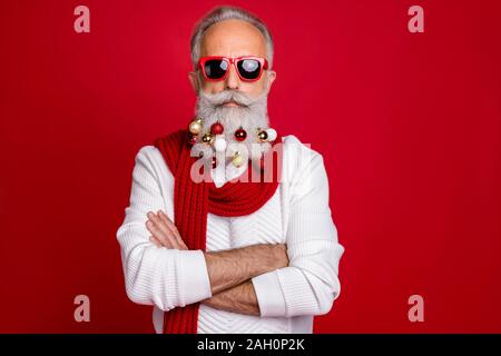 Portrait de l'homme d'affaires retraité cool avec des lunettes eyewear traversant ses mains wearing white sweater sur fond rouge isolé Banque D'Images