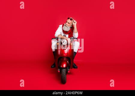 Photo pleine longueur d'une personne âgée de toucher ses lunettes eyewear s'asseoir sur un vélo pense que porter des pantalons pantalon cavalier blanc sur rouge isolé Banque D'Images