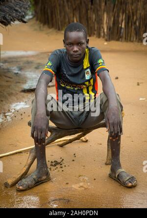 Larim tribe boy s'asseoir sur un siège en bois, Boya, montagnes Imatong, au Soudan du Sud Banque D'Images