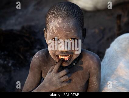 Smiling Mundari tribe boy couvert de cendres en prenant soin de longues cornes vaches dans un camp, l'Équatoria central, Terekeka, au Soudan du Sud Banque D'Images