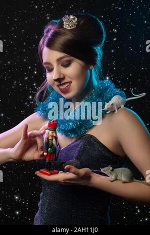Fille en costume reine de la souris joue avec Casse-noisette toy sur fond noir Banque D'Images