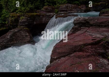 Rushes cascade sur rochers rouges dans les montagnes du Montana Banque D'Images