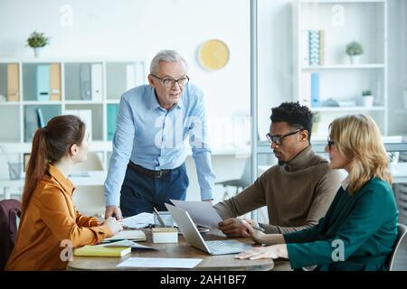 Les gens d'affaires multiethniques assis à la table et à l'écoute de man au cours de réunions d'affaires au board room Banque D'Images