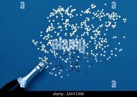 Bouteille de champagne avec confetti stars dans les couleurs. Mise à plat de Noël, anniversaire, fête du Nouvel An concept. Couleur de l'année 2020 classic Banque D'Images