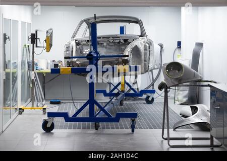 Voiture sur mesure en cours de construction en atelier. Corps de voiture de sport, location de cadre assemblé par la mécanique. Châssis auto métallique dans l'air, location de squelette en service Banque D'Images