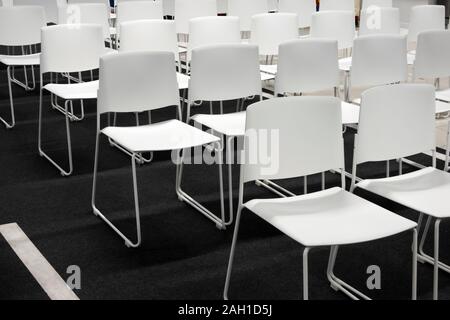 Des rangées de chaises en plastique blanc pour les réunions officielles, conférence, conférences, des cérémonies. Salle pleine de chaises blanches vides. Banque D'Images