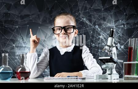 Petite fille intelligente scientifique à lunettes à 24 dans la classe de laboratoire. La recherche et l'éducation dans l'école. Laboratoire de chimie avec microscope, flacons et Banque D'Images