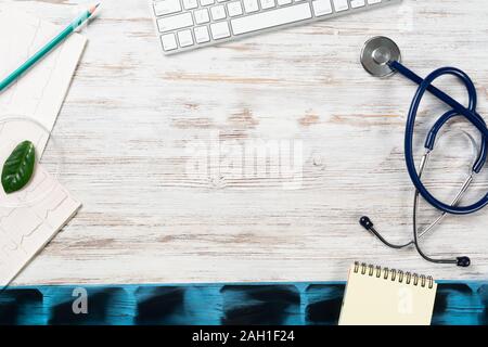 Les médecins de bureau avec les fournitures médicales. Clavier d'ordinateur, x-ray image, stéthoscope et cardiogramme se trouve sur un bureau en bois. Les soins de technologie concept w Banque D'Images