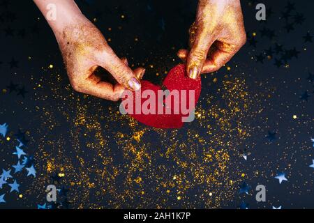 Valentines Day concept. Woman's hands holding coeur brisé. Cœur brisé sur fastive arrière-plan. Banque D'Images