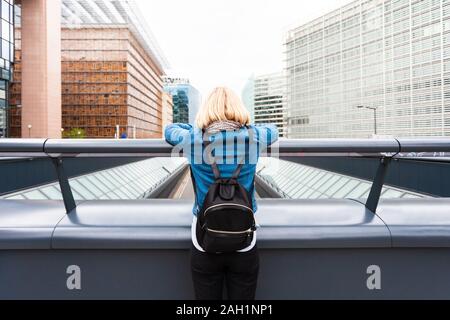 Une femme se tient sur un pont avec son dos à la caméra dans le contexte d'un quartier de bureaux modernes, Belgique Banque D'Images