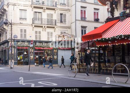 Piétons passant devant une boulangerie artisanale et un café avec une enseigne rouge sur une rue de Paris, France. Banque D'Images