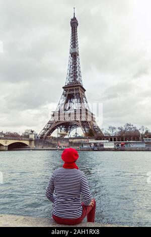 L'homme est assis sur le bord d'une rivière et ressemble à la Tour Eiffel Banque D'Images