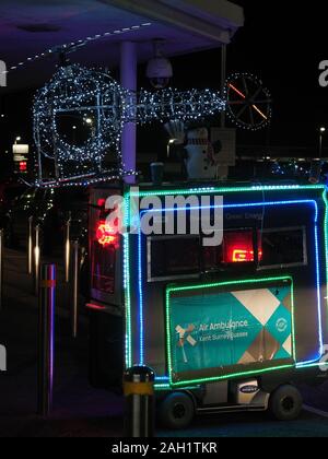 Sheerness, Kent, UK. Dec 23, 2019. Un scooter de mobilité décorées dans des lumières de Noël et jouer de la musique vu en dehors de Tesco à Sheerness collecter de l'argent pour l'air ambulance. Credit : James Bell/Alamy Live News Banque D'Images