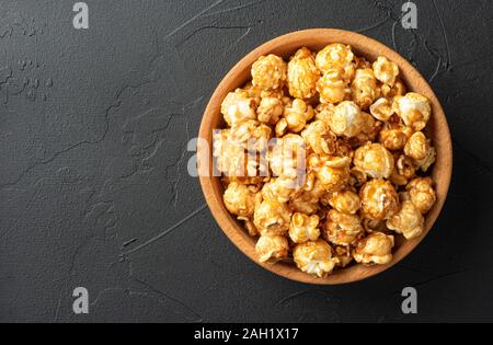 Maïs soufflé au caramel bol en bois sur fond sombre Banque D'Images