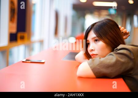 Lonely sad girl en attente de quelqu'un et se trouvant sur la table rouge Banque D'Images