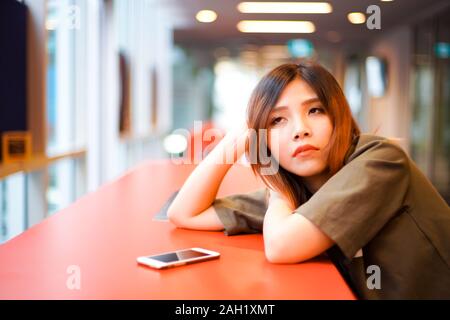 Lonely sad girl en attente de quelqu'un et se trouvant sur la table rouge Banque D'Images