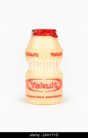 Une petite bouteille de boisson de lait probiotique sucré Yakult tourné sur un fond blanc. Banque D'Images