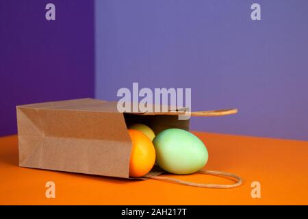 Composition de Pâques les oeufs de Pâques colorés multicolores sur sac en papier craft sur fond pastel. Plaisir des vacances de Pâques. Banque D'Images
