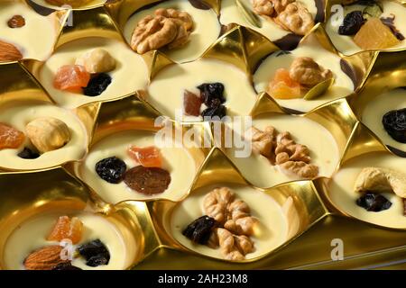 Bonbons de chocolat à la main dans une boîte pour l'arrière-plan, un aliment sucré, décoré de noix, fruits secs, fruits confits Banque D'Images