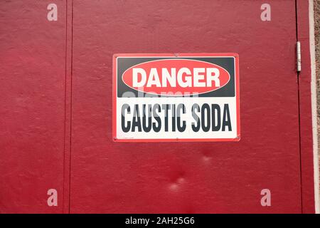 La soude caustique panneau d'avertissement sur une porte rouge, près d'une usine de traitement de l'eau dans la région de Renton, Washington, USA ; danger de la soude caustique. Banque D'Images