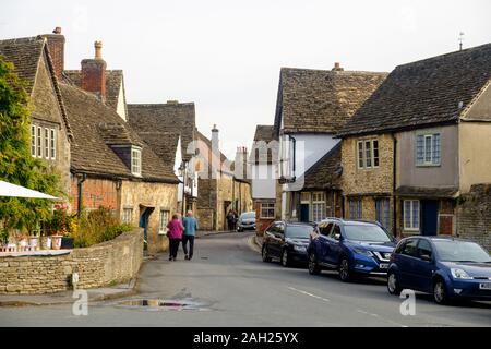 Un couple marche bras dessus bras dessous dans les rues de Lacock, un petit village avec des maisons traditionnelles. Cet emplacement sert souvent de décor de cinéma. Banque D'Images