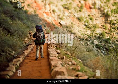 Randonneur solitaire marchant le long d'un chemin de terre avec un grand sac sur son dos. Banque D'Images