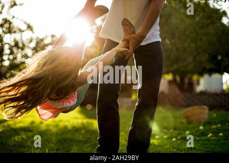 Man spinning espièglerie sa jeune fille autour de l'arrière-cour Banque D'Images