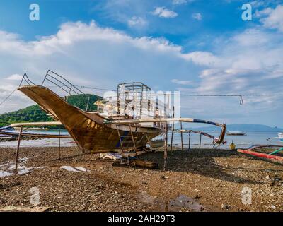 Un bateau en bois outrigger, connu localement sous le nom d'une banque, en construction sur une île plage à marée basse. Interisland Bancas sont utilisés pour les voyages. Banque D'Images