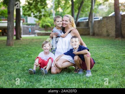 Jeune femme et trois jeunes garçons en parc d'été. La mère et les enfants à l'extérieur. Banque D'Images