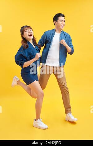 Attractive smiling Young Asian couple d'être heureux et surpris isolé sur fond jaune studio Banque D'Images