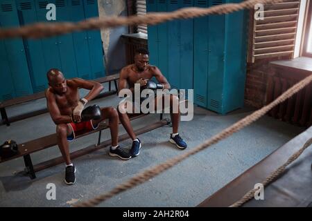 Deux boxeurs africains assis sur un banc et portant des gants de boxe et la préparation de l'entraînement sportif Banque D'Images