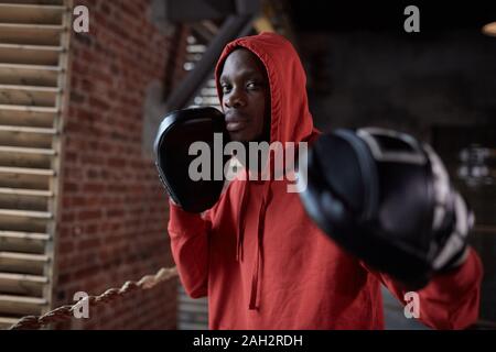 Portrait de jeunes Africains en boxer, culotte, portant des gants de boxe et posant à huis clos tout en se tenant dans une salle de sport Banque D'Images