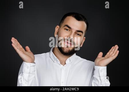 Portrait de jeunes surpris beau barbu avec l'expression du visage choqué sur fond noir Banque D'Images