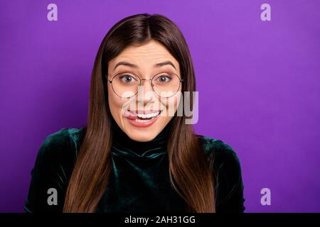 Portrait de jeunesse lovely léchant ses lèvres à la recherche de l'appareil photo à porter col roulé noir sur fond violet pourpre isolés Banque D'Images