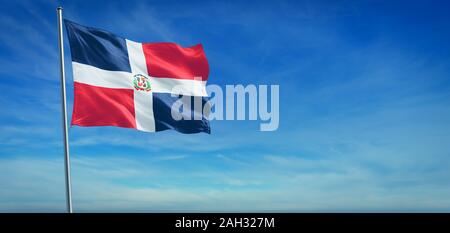 Le drapeau national de la République dominicaine dans le vent en face d'un ciel bleu clair Banque D'Images