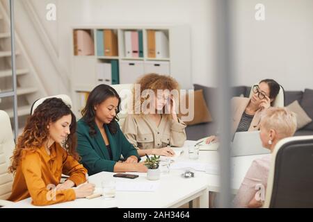Groupe de cinq femmes de l'âge et l'origine ethnique différentes ayant réunion d'affaires dans la salle du conseil d'angle horizontal haut shot Banque D'Images