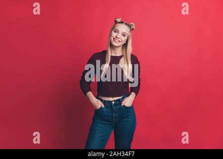 Photo de dame millénaire incroyable tenant les mains dans les poches l'humeur positive porter des jeans et pull-over en tricot rouge fond couleur pastel isolés Banque D'Images