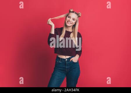 Photo de dame millénaire incroyable tenant les mains dans les poches l'humeur positive jouant avec curl long pull tricoté usure et jeans rouge pastel isolés Banque D'Images