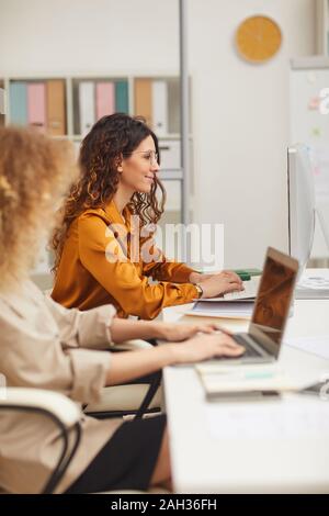 Les femmes qui travaillent sur des ordinateurs de bureau moderne en vue de côté vertical shot Banque D'Images