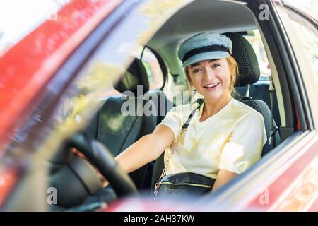 Happy woman conducteur derrière le volant voiture rouge Banque D'Images