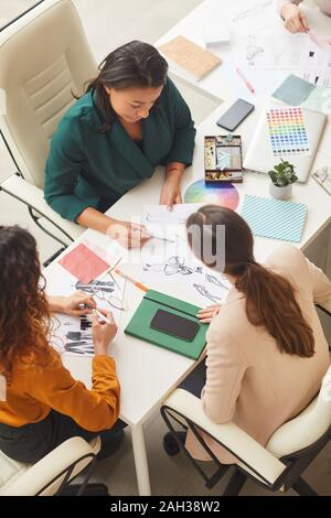 Groupe d'ethnies diverses jeunes femmes travaillant sur la conception des vêtements ensemble concept tourné l'angle vertical haut Banque D'Images
